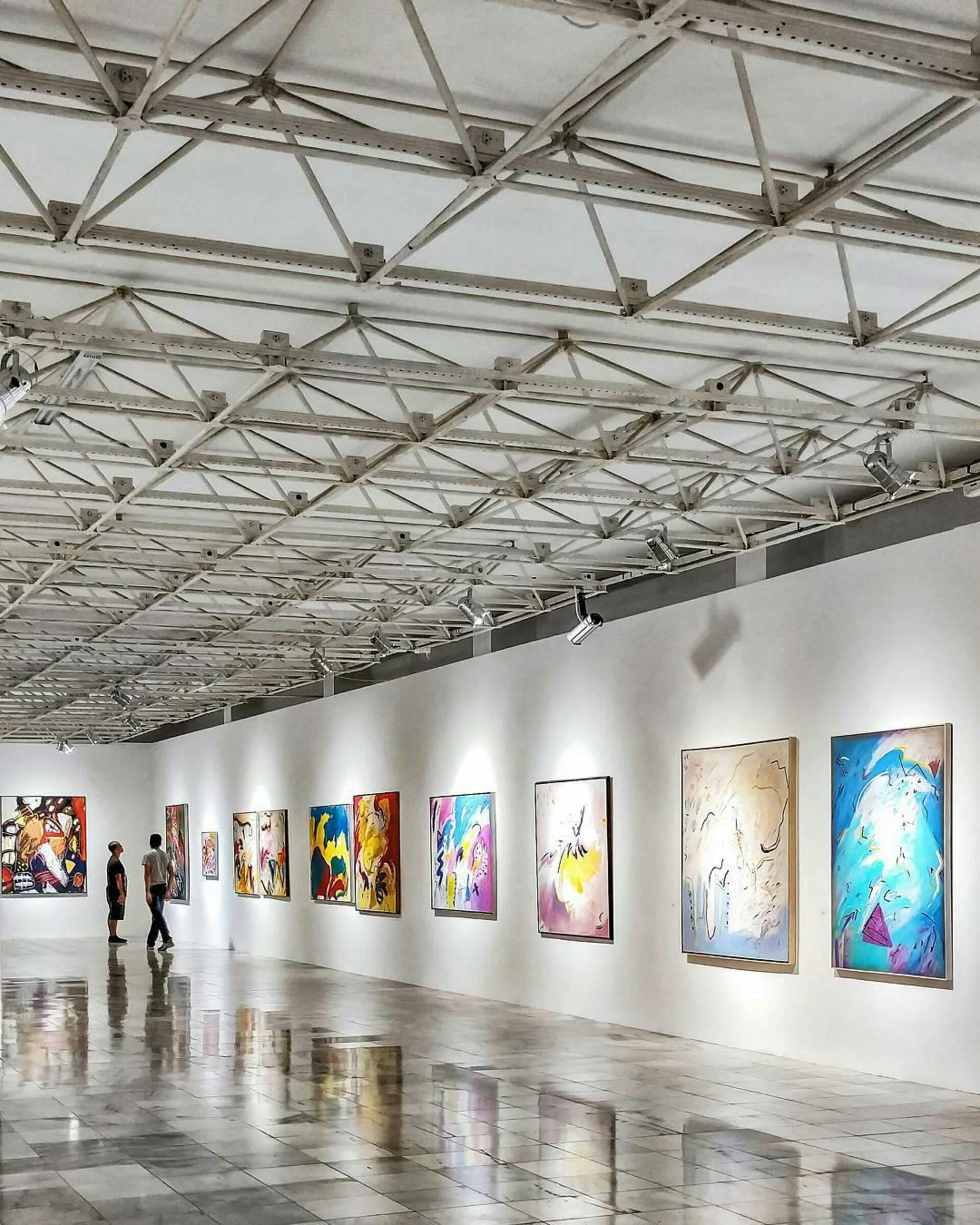 Wide shot of an art gallery with multiple framed pieces of art hanging on the walls