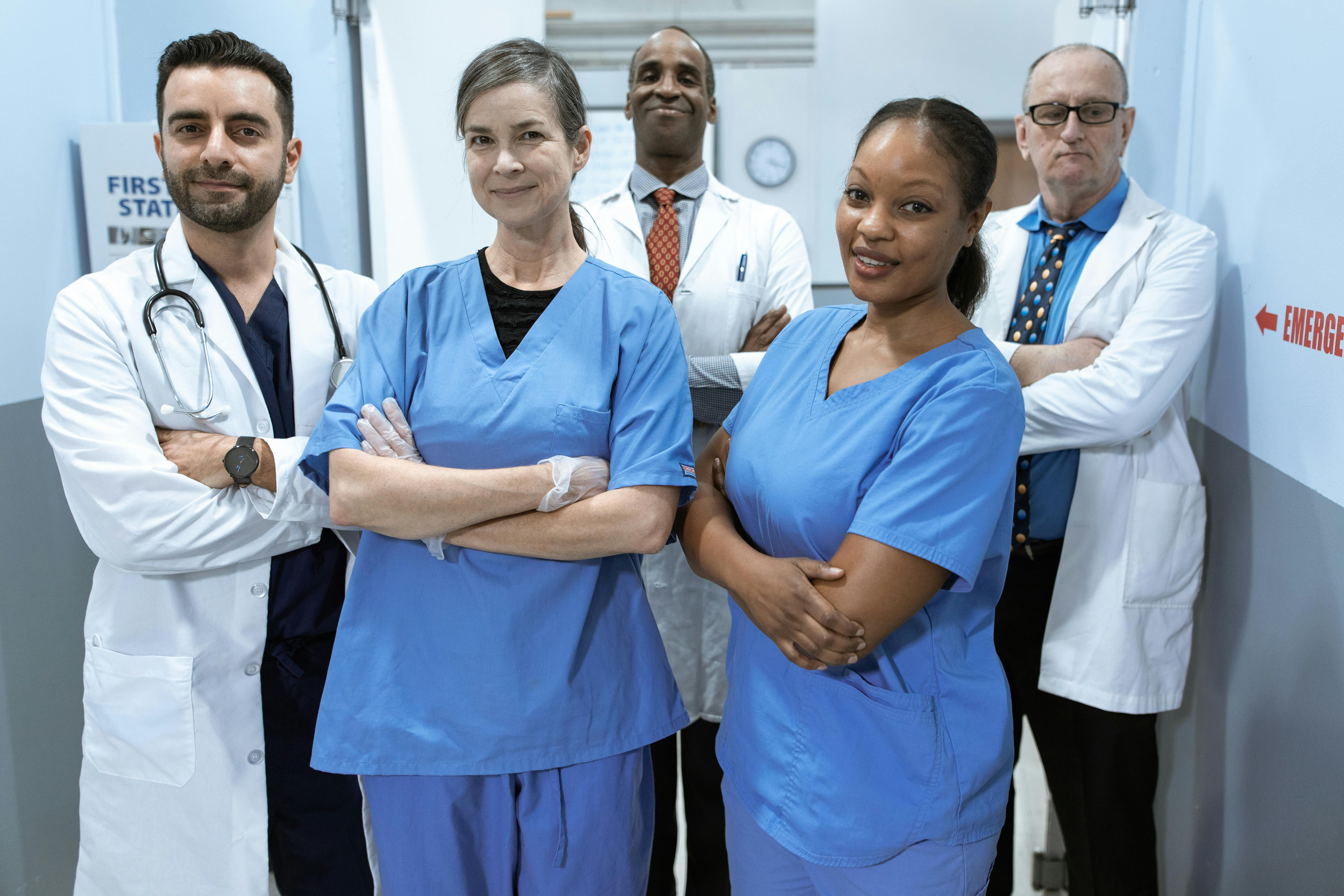 A group of nurses and doctors posing in a hospital hallway for a picture