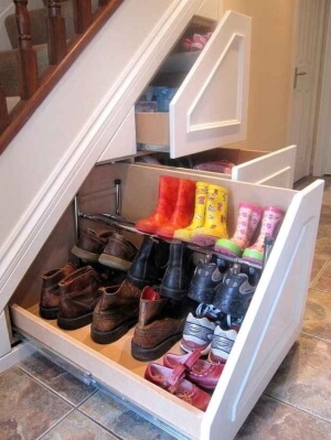 Pull-out shelving from underneath the stairs filled with shoes