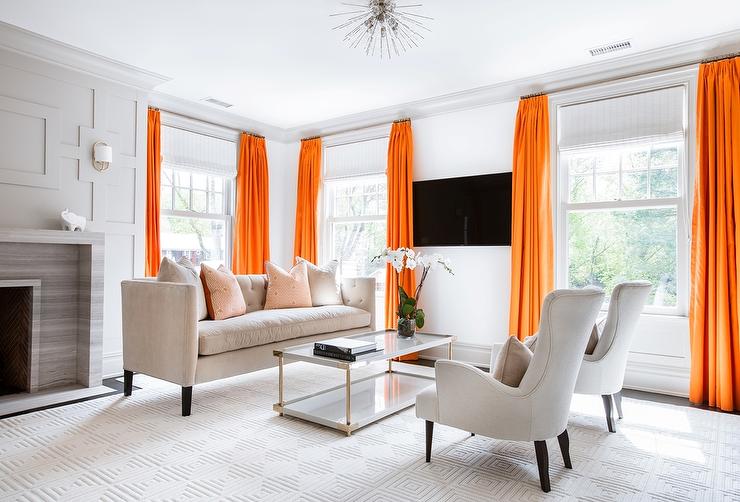 relaxing grey living room with a pop of color featuring orange curtains