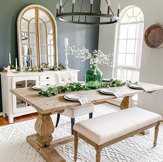 rustic dining room decorated in a farmhouse home decor style. Wooden table, mixed metal light fixture, greenery on the table