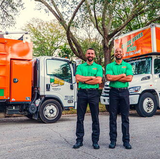 College Hunks Movers posing with two moving trucks. 