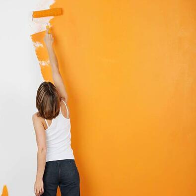 Woman painting a wall orange