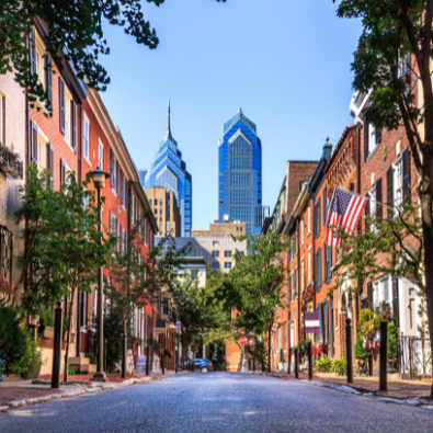 Philadelphia skyline view from a street full of traditional rowhouses.