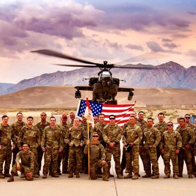 US Military & College HUNKS franchise owner hold US Flag in front of Apache helicopter