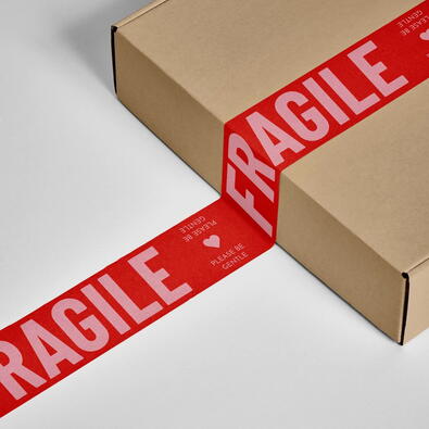 Cardboard box sealed with red tape labeled FRAGILE, used for shipping and handling delicate items