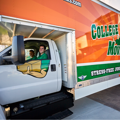 Two College HUNKS movers smiling from the inside of a moving truck.