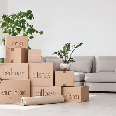 Stack of labeled cardboard moving boxes in a bright room, ready to be packed