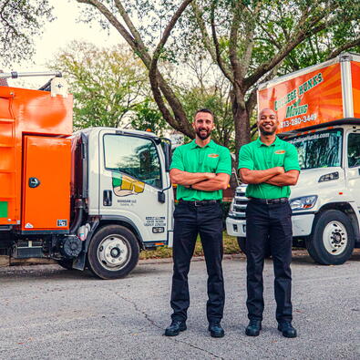 College Hunks Movers posing with two moving trucks. 