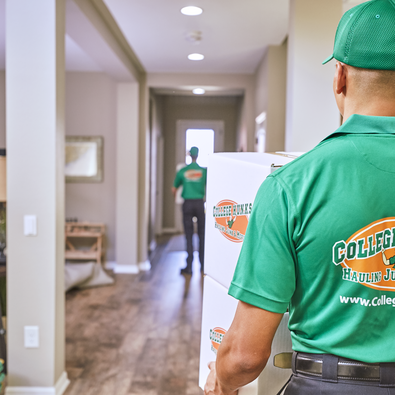 College Hunks employee carrying moving boxes inside a house