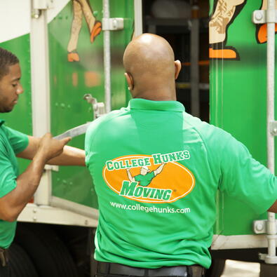 Two College Hunks movers closing a moving truck. 