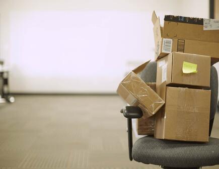 Stack of brown boxes on gray office chair