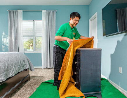 College HUNKS mover covering a dresser with a moving blanket