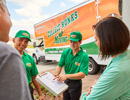 Two College HUNKS movers showing paperwork to a couple.