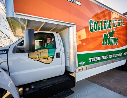 Two College HUNKS movers smiling from the inside of a moving truck.