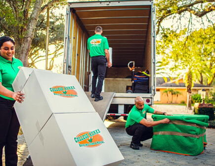 Three College HUNKS movers unloading items from the back of a moving truck