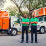 College Hunks Movers posing with two moving trucks. 